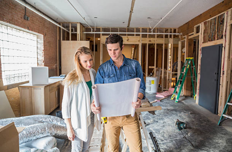 un homme et une femme qui regardent des plans dans une maison en construction